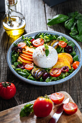Salad with burrata cheese, peaches, tomato, plum, cherries and arugula. Italian healthy meal with lot of vitamins. Super food.