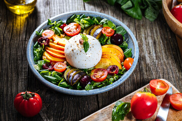 Salad with burrata cheese, peaches, tomato, plum, cherries and arugula. Italian healthy meal with lot of vitamins. Super food.