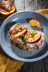 Spread with cream cheese on bread with rucola, nuts and peach. Healthy summer brunch. Vitamins and minerals