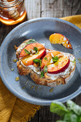 Spread with cream cheese on bread with rucola, nuts and peach. Healthy summer brunch. Vitamins and minerals