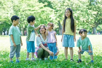 緑地で、一列に並ぶ子どもたちと女性