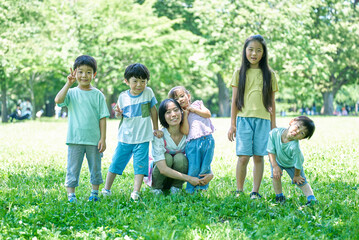 緑地で、一列に並ぶ子どもたちと女性