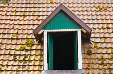 Bay window with an open window on an old building roof.
