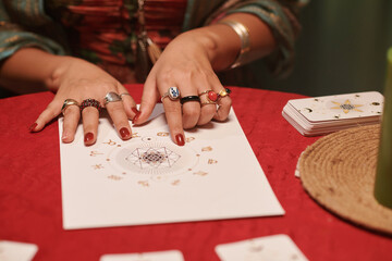 Closeup image of astrologer examining natal chart of client to check love compatibility of her and...