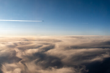 Blick aus dem Fenster im Flugzeug über den Wolken bei Sonnenuntergang