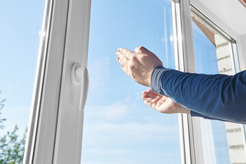 Man's arms reaches for window. Hands on background of plastic window frame. Concept of asking for help or finding way out, freedom, sharing your feelings.