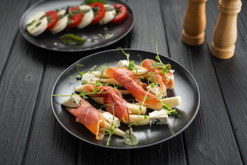 Appetizer with pear, prosciutto ham and blue cheese on a dark wooden background, Healthy eating for weight loss.