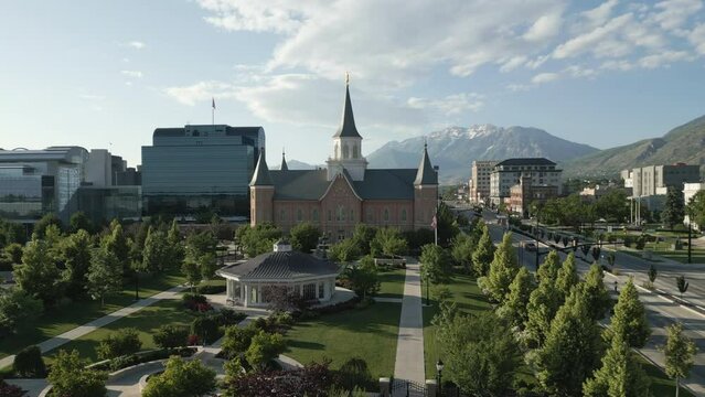 LDS Temple in city center of Provo, Utah, distant mountain backdrop. Aerial rise.