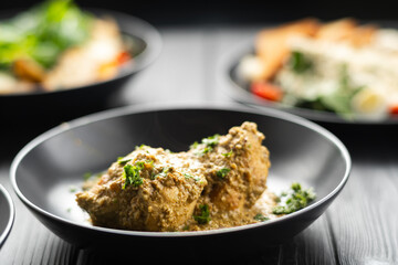 Fried chicken breast in a creamy garlic sauce on a plate on a black wooden table in a restaurant