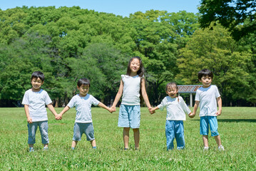 Fototapeta premium 草原で手を繋いで並ぶ子どもたち