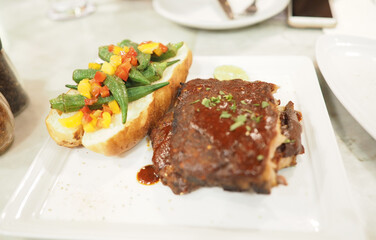Grilled beef steak with salad and bread on white plate in restaurant