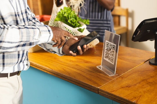 Senior african american man paying with smartphone using qr code at health food organic grocery shop