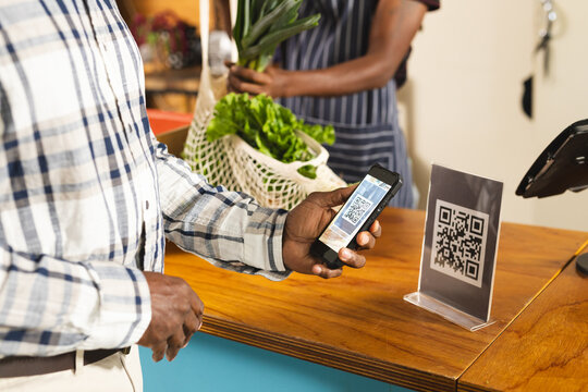Senior african american man paying with smartphone using qr code at health food organic grocery shop