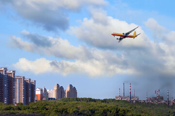 A cargo airliner delivers cargo to the city from the industrial zone. The concept of logistics delivery of goods from industrial regions with poor environmental conditions. Smoke from factories.