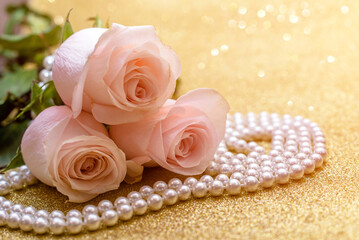 Obraz na płótnie Canvas Pink rose and pearl necklace on a shiny gold background 