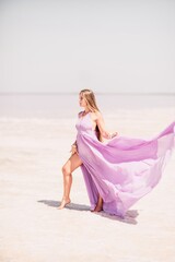 Fototapeta na wymiar Woman pink salt lake. Against the backdrop of a pink salt lake, a woman in a long pink dress takes a leisurely stroll along the white, salty shore, capturing a wanderlust moment.