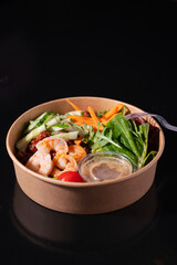Bowl with shrimps, carrots, cucumbers, beans and vegetables with herbs, on a black background. Healthy food concept