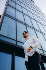 a businessman stands near a glass building