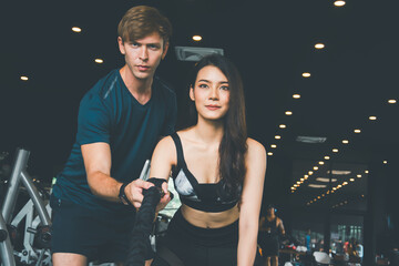 Mixed race Asian women, man trainer exercising using battle rope during strength training body at gym, happy in fitness to exercise, concept burning excess body,with exercises that the trainer plans