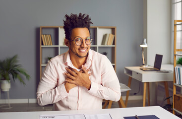 Fototapeta premium Smiling biracial man looking at screen having video call. Headshot portrait of young businessman making conference video call, having distant job interview, recording video blog
