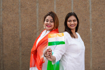 Indian woman holding tricolor flag in hand and celebrating national festival.