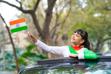 indian little girl exit from car sunroof and waving national flag.