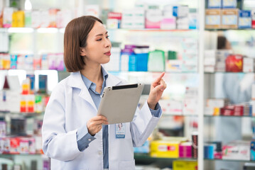 Fototapeta na wymiar Pharmacist asian woman using digital tablet for check medicine inventory in drug store, Medical service online, Telemedicine to giving medical information to online customer and patient.