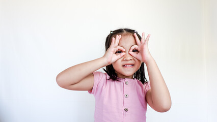 child seriously doing funny faces making with finger glasses shape like glasses looking through binoculars. isolated on light color background.