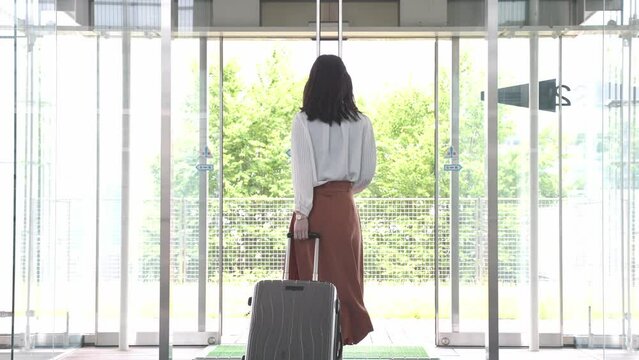 スーツケースを引きながら歩く女性