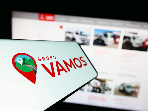 Stuttgart, Germany - 07-06-2023: Mobile phone with logo of Brazilian truck rental company Grupo Vamos on screen in front of website. Focus on center-left of phone display.