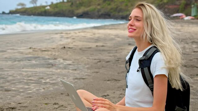 Freelance woman work open air. Happy digital nomad use laptop computer near sea beach. Smile girl type macbook. Female person enjoy job. Pretty ocean view. Casual tourist rest outdoor. Marine coast.