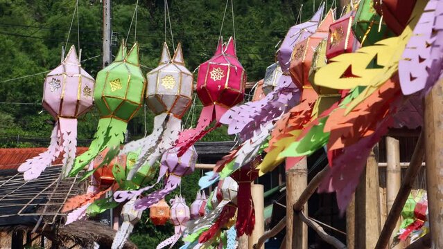 Decorative lanterns flutter in the wind suspended from a bamboo footbridge in northern Thailand