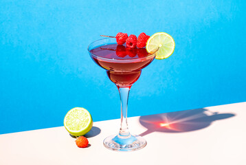 La Bomba Daiquiri alcoholic cocktail drink with white rum, lime juice, syrup, pomegranate and raspberries, summer blue bright background, hard light and shadows