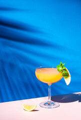Paddington alcoholic cocktail drink with rum, yellow liquor, grapefruit and lemon juice, marmalade and absinthe, summer blue bright background, hard light and shadows