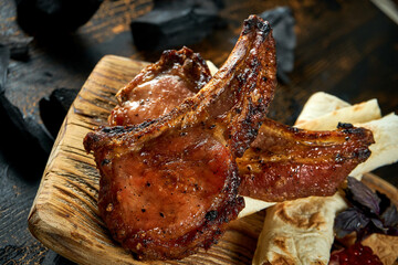 Pork steak on the bone grilled on a charcoal barbecue on a wooden board. Georgian shashlik