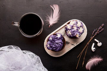 Purple aesthetics trendy floral cupcake and cup of coffee near wireless headphones. French no sugar dessert. Music, relaxation concept