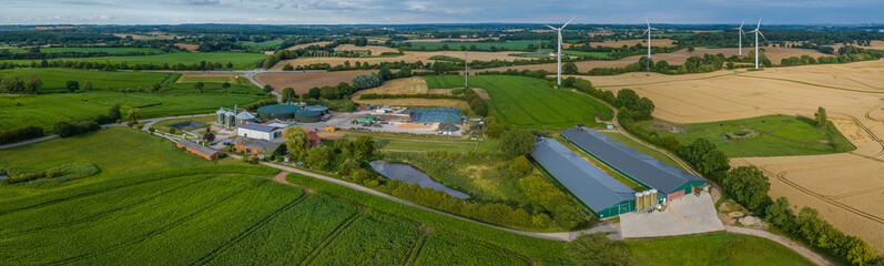 Aerial view of modern agriculture farm with agricultural fields with corn, biogas plant, wind...