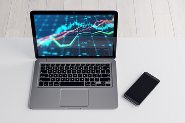Close up and top view of laptop and cellphone with forex chart on screen at white office workplace. Market, finance and online trading concept. 3D Rendering.