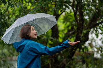 Attractive young asian woman smilingcarrying umbrella and wearing her coat while walking in the...
