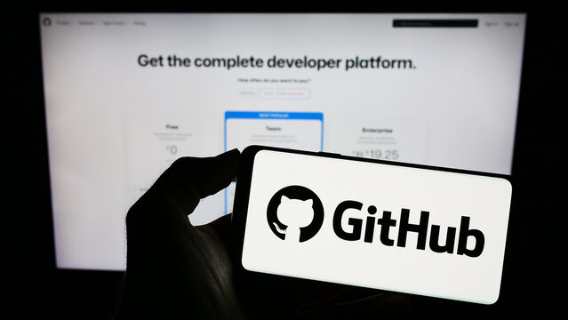 Stuttgart, Germany - 07-09-2023: Person holding cellphone with logo of US software development company GitHub Inc. on screen in front of business webpage. Focus on phone display.