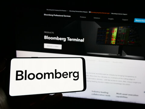 Stuttgart, Germany - 07-09-2023: Person holding mobile phone with logo of American financial data company Bloomberg L.P. on screen in front of web page. Focus on phone display.