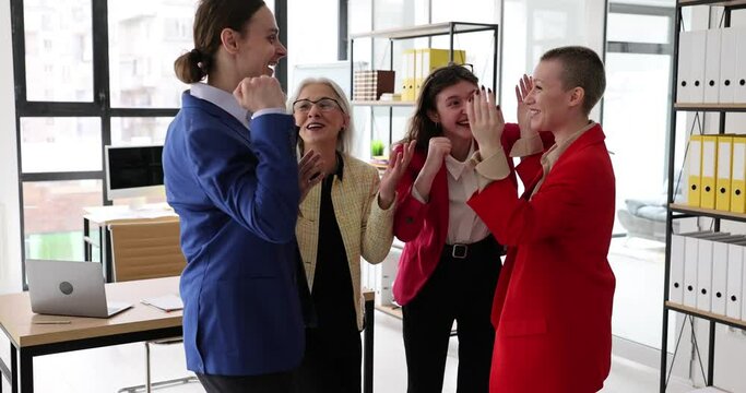 Office female employees have fun after successful business offer from company. Colleagues celebrate important proposition raising hands slow motion