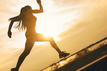 Silhouette of young woman running sprinting on road. Fit runner fitness runner during outdoor...