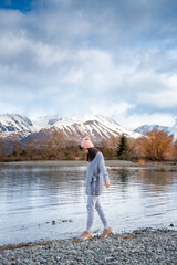 Fototapeta na wymiar Asian female model enjoy the beautiful scenic sunrise view of Lake Pukaki east bank, with their mesmerizing turquoise hue and reflect the majestic snow-capped Southern Alps.