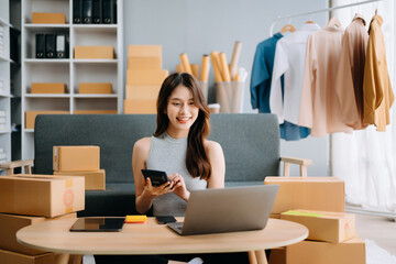 Startup small business SME, Entrepreneur owner woman using smartphone or tablet taking receive and checking online purchase shopping order to preparing pack product box. . - obrazy, fototapety, plakaty