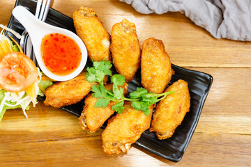 Fried chicken wings on a black plate in a restaurant.