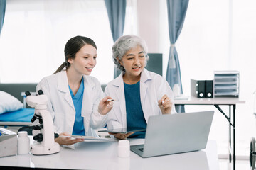 Obraz premium Medical Research Laboratory: Two scientists working, using digital tablets, analyzing samples, talking, developing biotechnology.