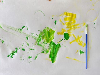 photo of a blue brush and abstract hand-drawn green and yellow brush strokes. View from above