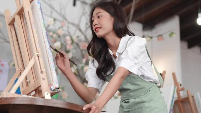 Beautiful Asian female artist working on abstract painting, painter creating modern art