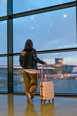 Travel.young woman at airport at window with suitcase waiting for plane, girl waiting for departure...